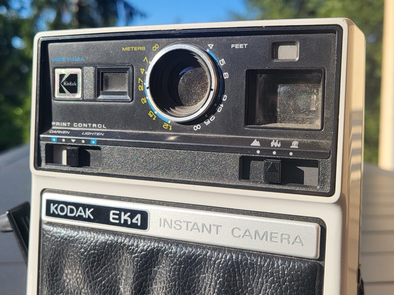 Un appareil photo instantané Kodak EK4 posé sur une table en terrasse, au soleil