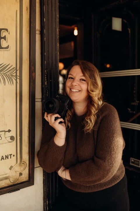 Solène Doux, photographe de mariage, souriante, son appareil photo à la main